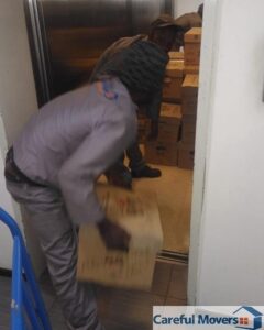 Careful Movers crew moving boxed IT equipment through a building service lift